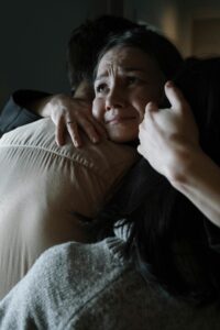 A sincere moment of emotional support as two people embrace tenderly in a dimly lit room.